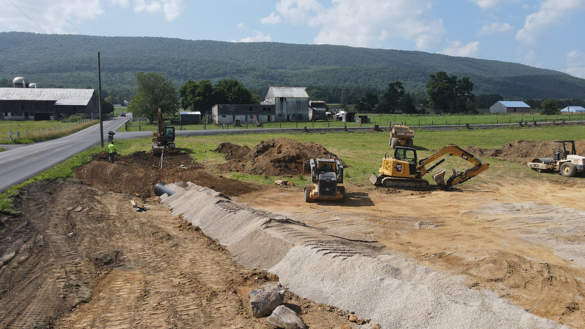 Excavators, skid steer, roller and haul truck working across a job site